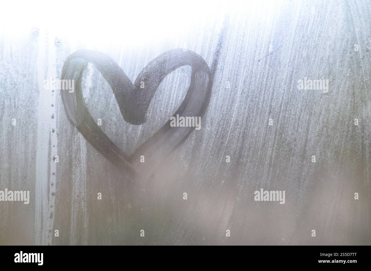 Eine herzförmige Zeichnung durch einen Finger auf einen Beschlagenen Glas im regnerischen Wetter gezeichnet Stockfoto