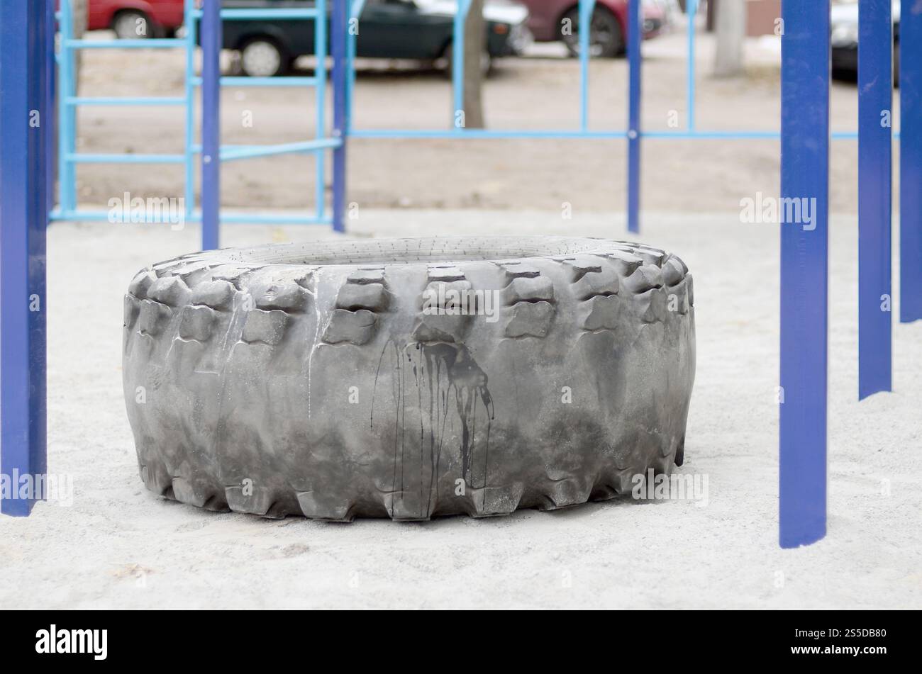 Ein großer schwarzer Reifen vor einem Straßensportplatz für Leichtathletik- und Crossfit-Training. Sportgeräte im Freien. Makrofoto Stockfoto