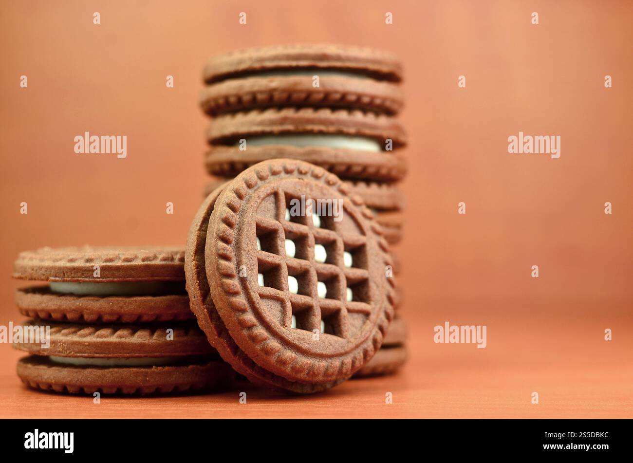 Ein Haufen Schokoladenkekse, gefüllt mit weißer Vanillecreme, liegt auf einer braunen hölzernen Oberfläche. Süße und leckere Sandwiches, runde Kekse. Detailliertes Essen Stockfoto
