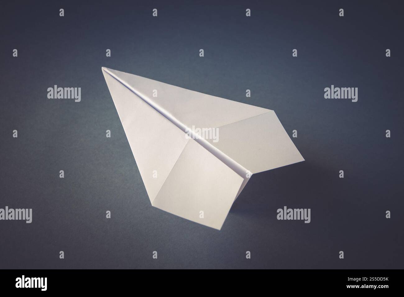 Weißes Papierflugzeug Origami isoliert auf einem leeren grauen Hintergrund. Weißes Papierflugzeug Origami isoliert auf grauem Hintergrund Stockfoto