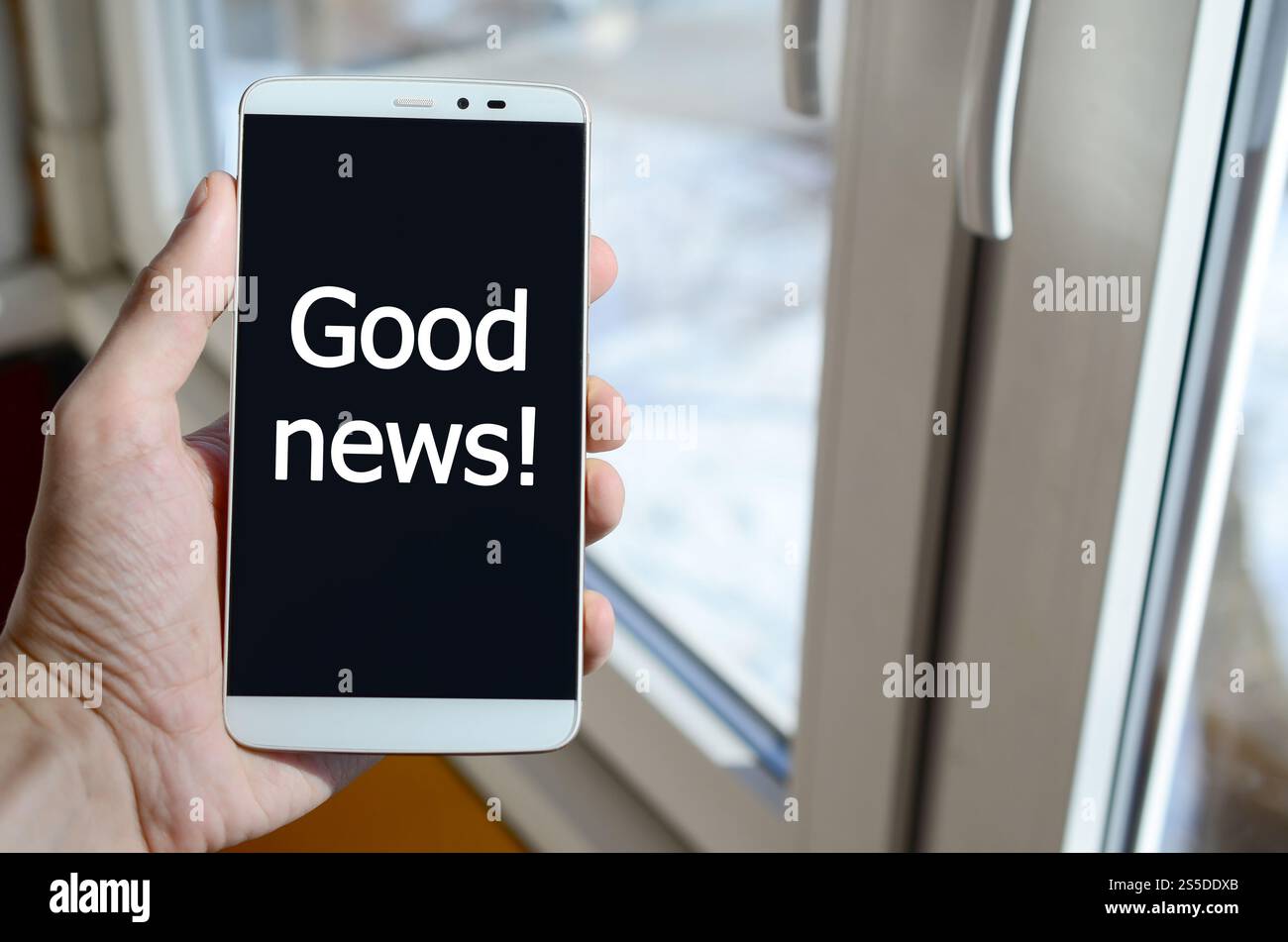 Eine Person sieht eine weiße Beschriftung auf einem schwarzen Smartphone-Display, das in der Hand hält. Gute Neuigkeiten! Stockfoto