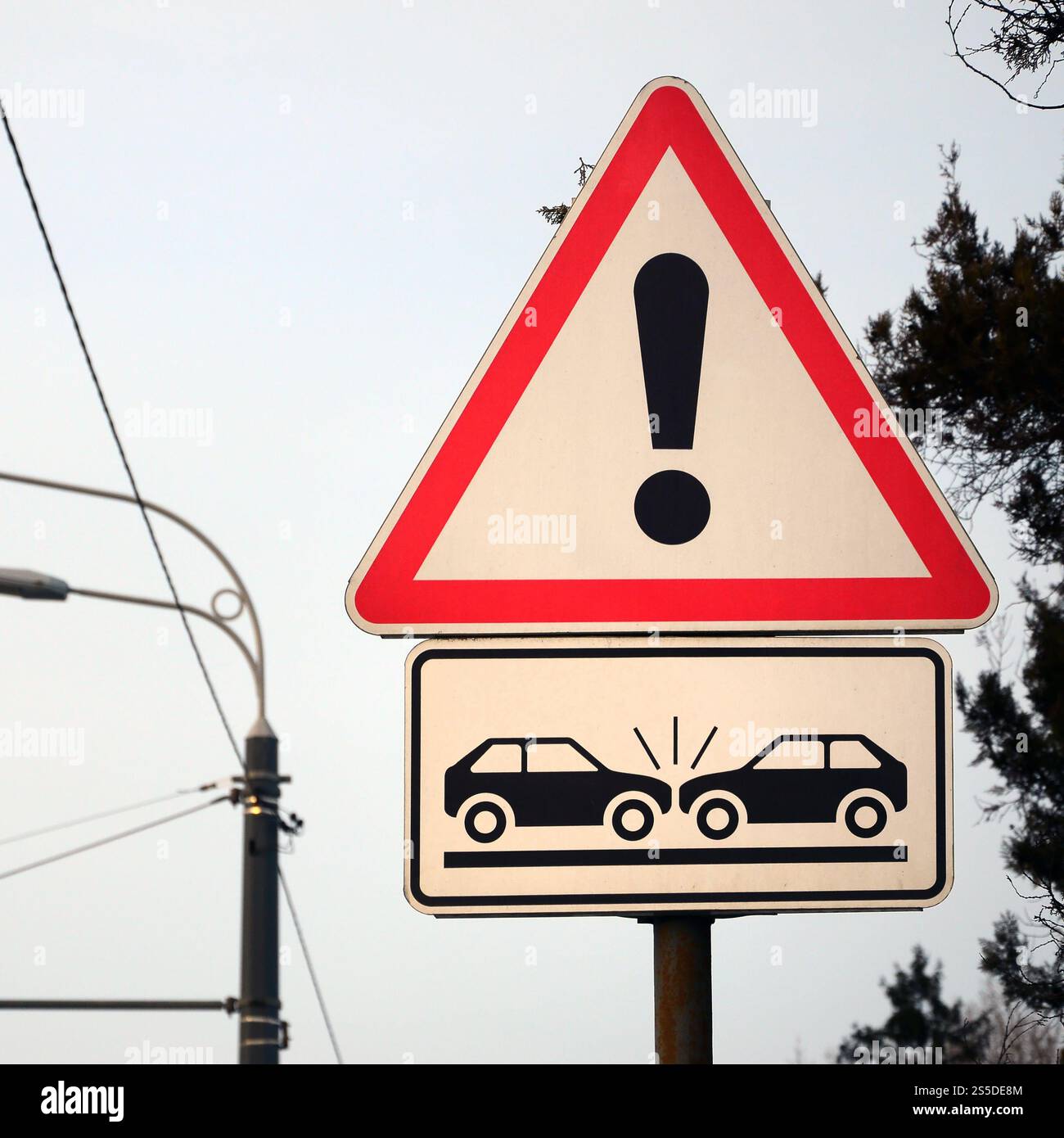 Hohes Kollisionsrisiko. Ein Straßenschild mit einem Ausrufezeichen und zwei Autos, die aufeinander abgestürzt sind Stockfoto