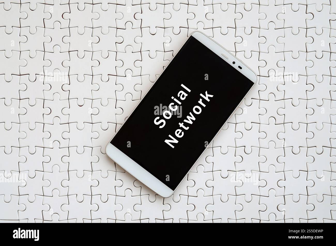 Eine moderne grosse Smartphone mit Touchscreen liegt auf einem weißen Puzzle im zusammengebauten Zustand mit Inschrift. Soziales Netzwerk Stockfoto