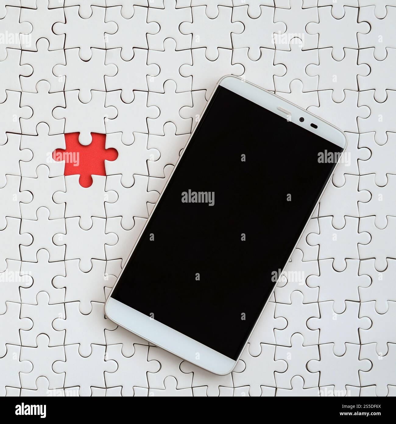 Ein modernes, großes Smartphone mit Touchscreen liegt in einem weißen Puzzle in zusammengebautem Zustand Stockfoto