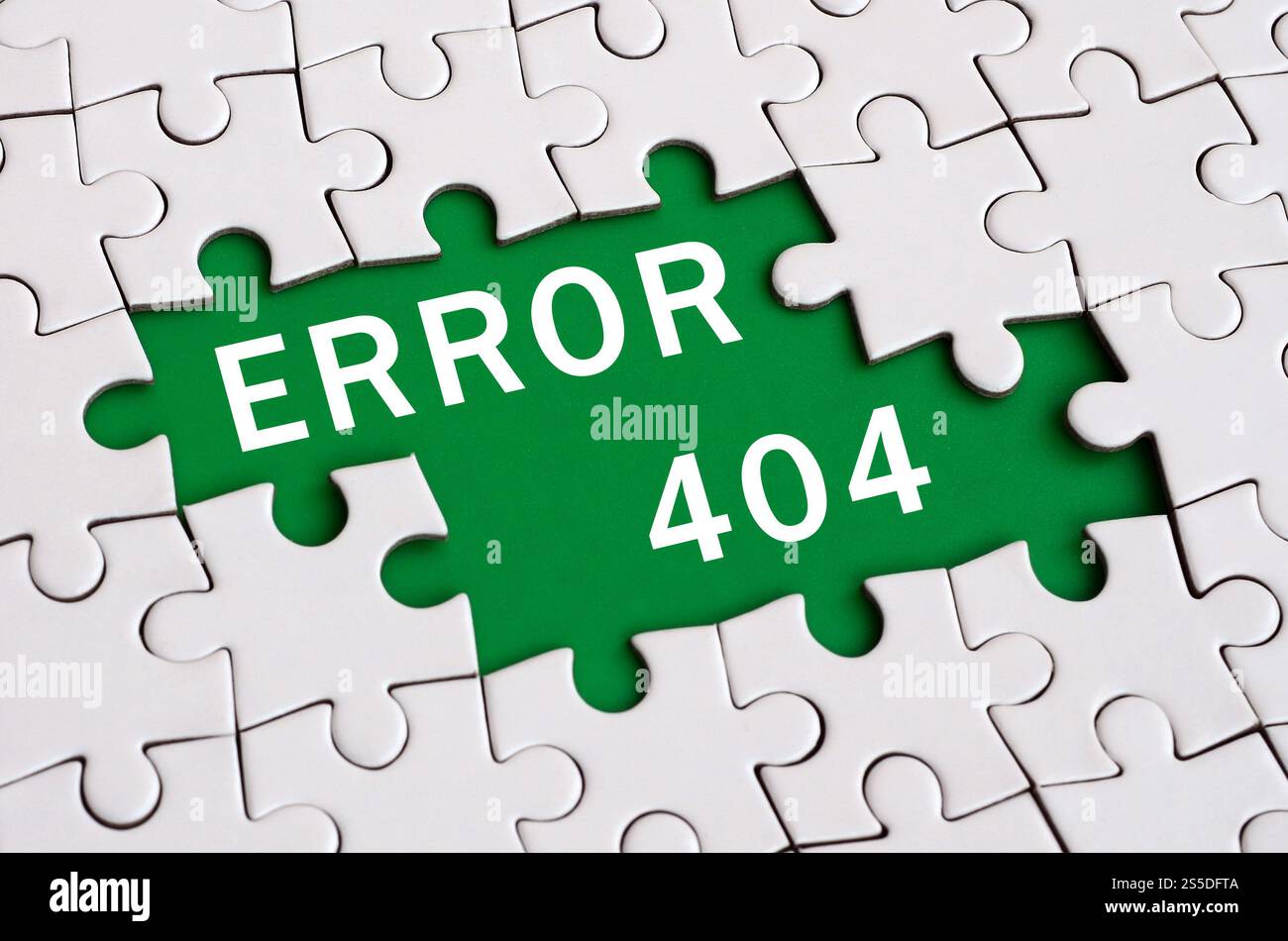 Weißes Puzzle im zusammengesetzten Zustand mit fehlenden Elementen, die einen grünen Raum mit weißer Inschrift bilden. Fehler 404 Stockfoto