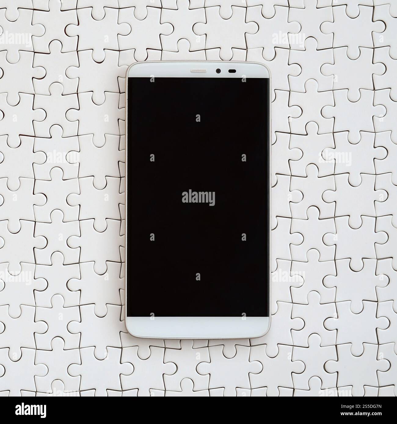 Eine moderne grosse Smartphone mit Touchscreen liegt auf einem weißen Puzzle im zusammengebauten Zustand Stockfoto