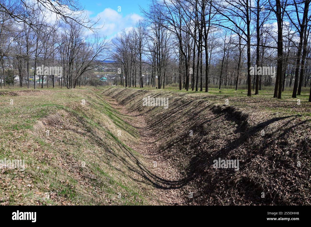 Frühling Landschaft mit einer tiefen Schlucht mit Laub durch eine Menge von Bäumen am Waldrand neben dem Dorf gefüllt Stockfoto