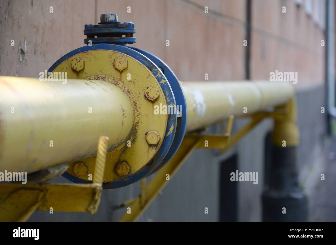 Gelbe Gasleitung vor der Wand des Wohngebäudes. Steinwand Textur Hintergrund natürliche Farbe. Gelbe Gasleitung vor dem Wohngebäude Stockfoto