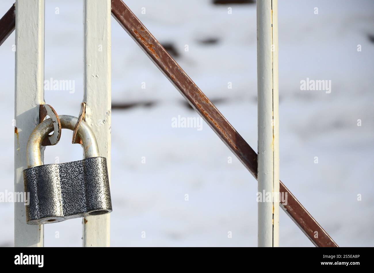 Ein großes graues Vorhängeschloss hängt an einem Metalltor Stockfoto