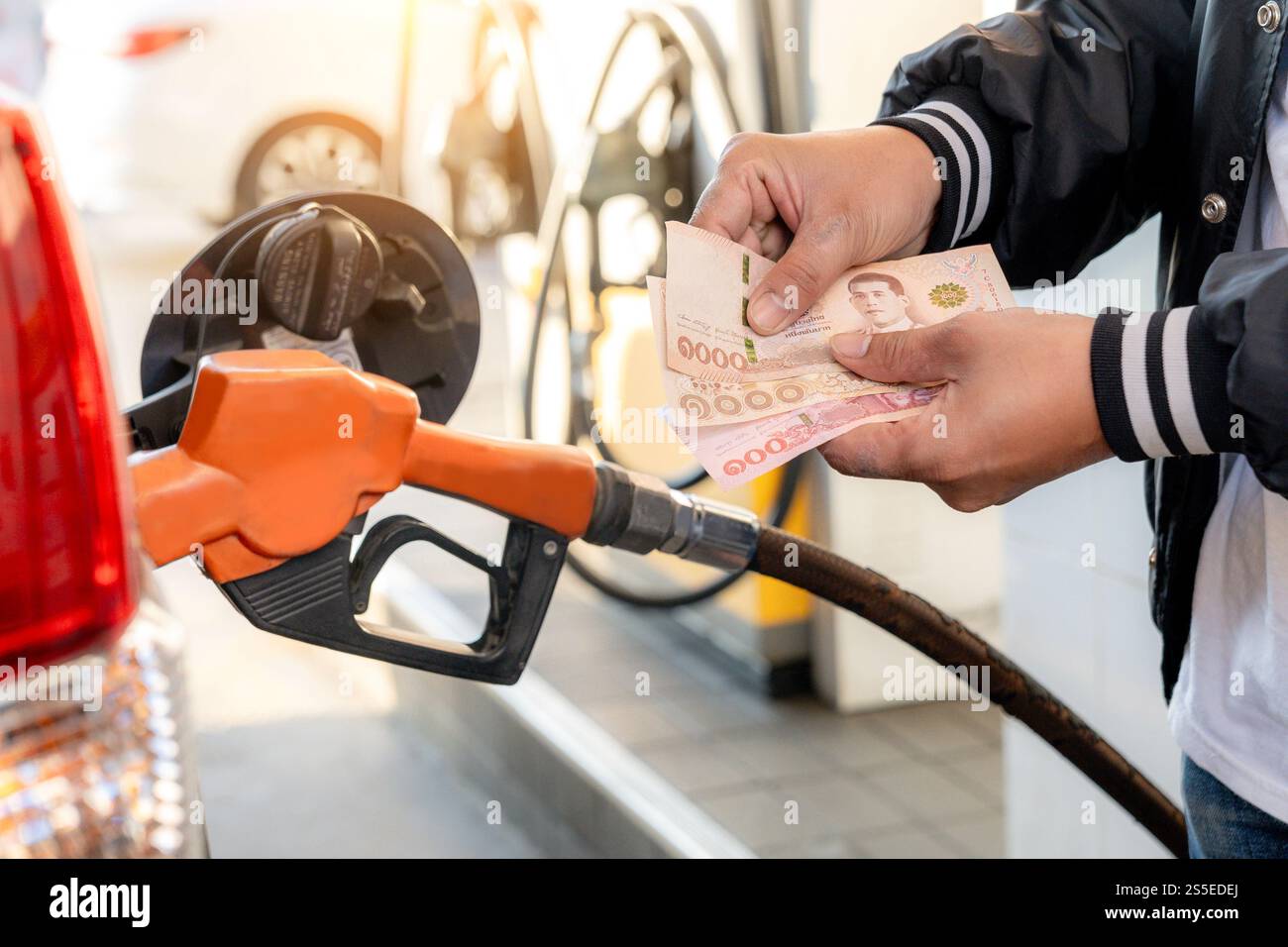 Ein Tankautomat an einer Tankstelle und ein Mann, der mit Bargeld bezahlt Stockfoto