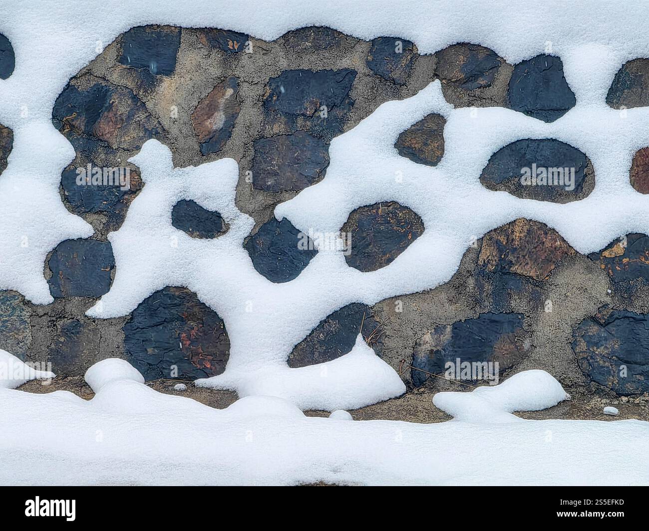 Steinmauer und Schnee: Ein harmonischer Winterrahmen Stockfoto