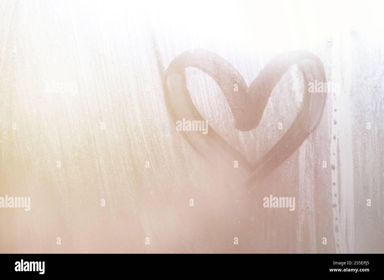 Eine herzförmige Zeichnung durch einen Finger auf einen Beschlagenen Glas im regnerischen Wetter gezeichnet Stockfoto