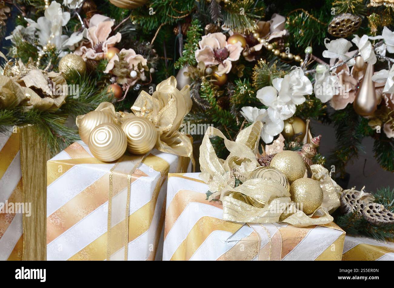 Foto von luxuriösen Geschenkboxen unter dem Weihnachtsbaum, Neujahrsdekoration, goldene Verpackung von Weihnachtsgeschenken, festliche Tanne mit dekoriert Stockfoto