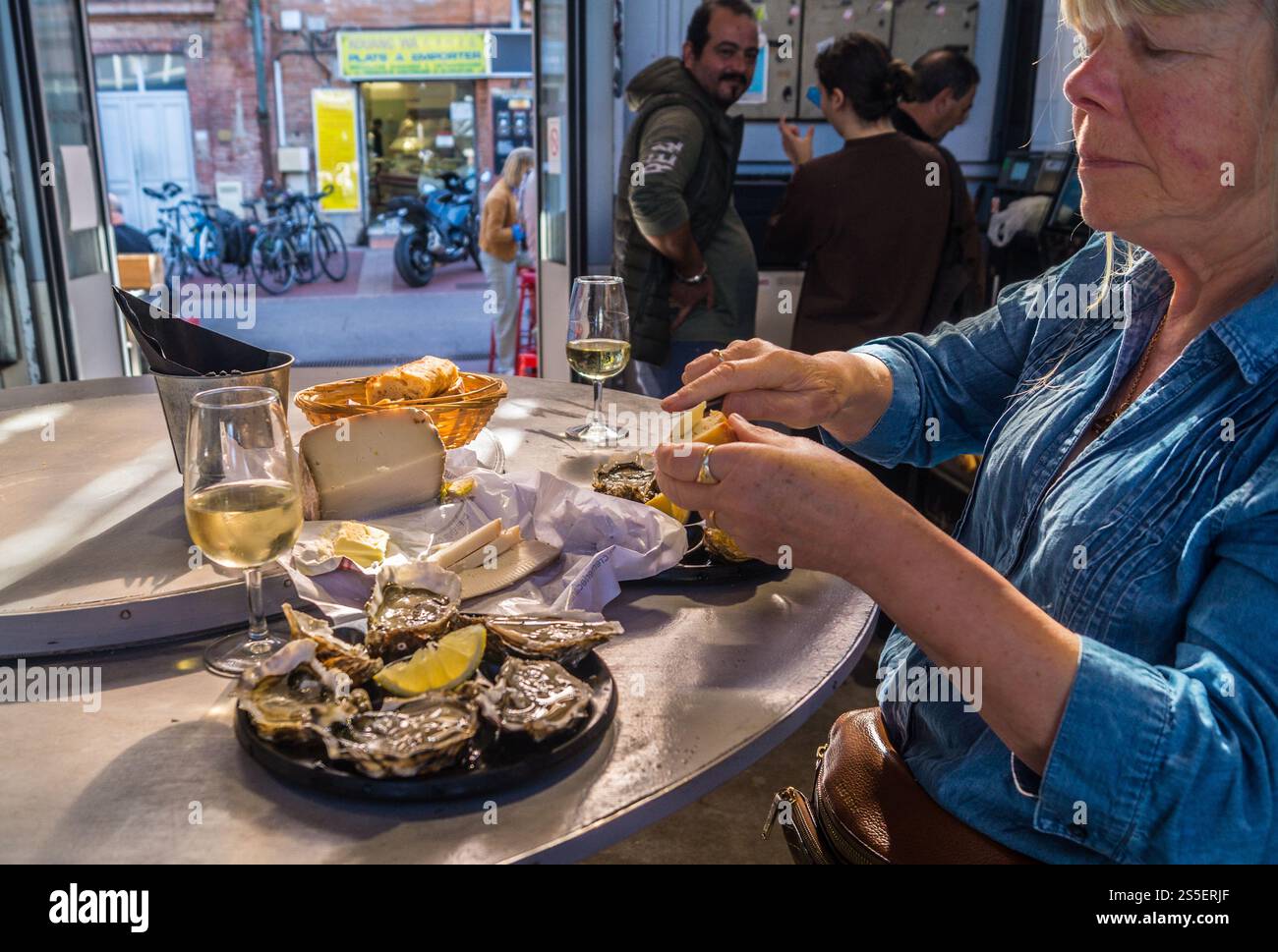 Mittagessen mit Austern, Brot, Käse und Weißwein in der Bar des Vedettes, dem überdachten Markt von Saint-Cyprien, Toulouse, Haute-Garonne, Occitanie, Frankreich Stockfoto