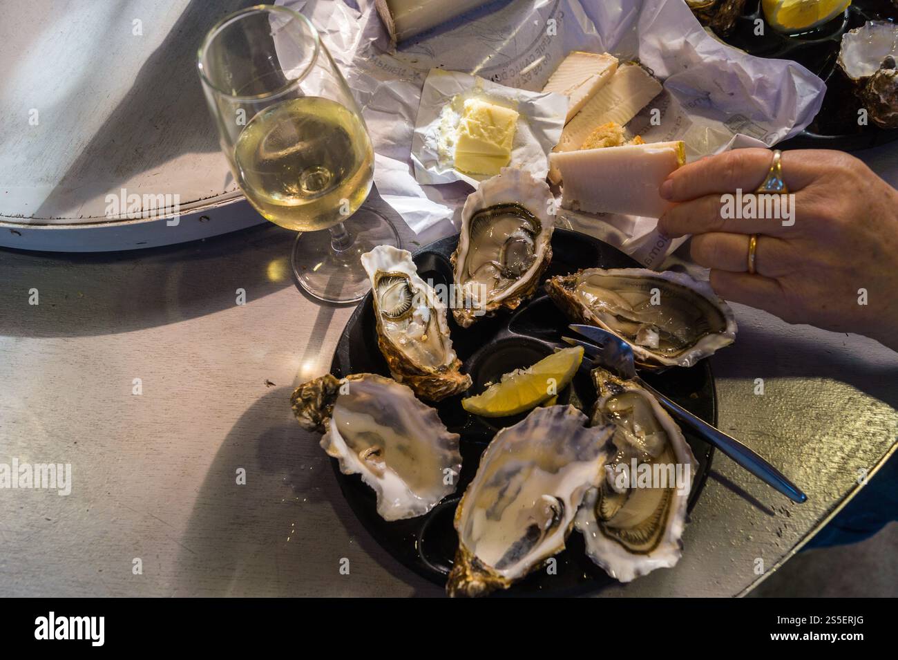 Mittagessen mit Austern, Brot, Käse und Weißwein in der Bar des Vedettes, dem überdachten Markt von Saint-Cyprien, Toulouse, Haute-Garonne, Occitanie, Frankreich Stockfoto