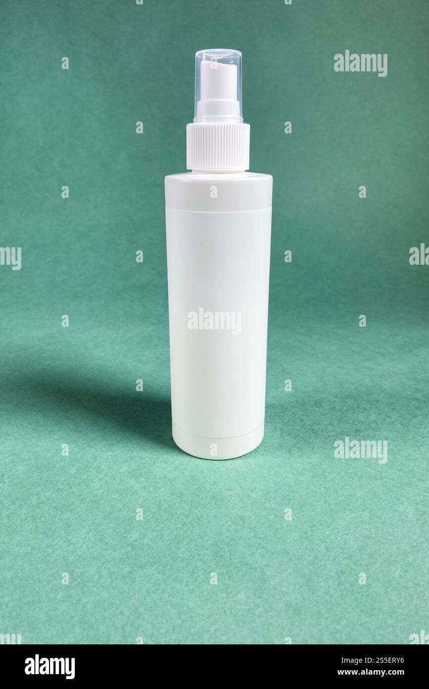 Eine weiße leere Sprühflasche aus Kunststoff auf grünem Papierhintergrund Stockfoto
