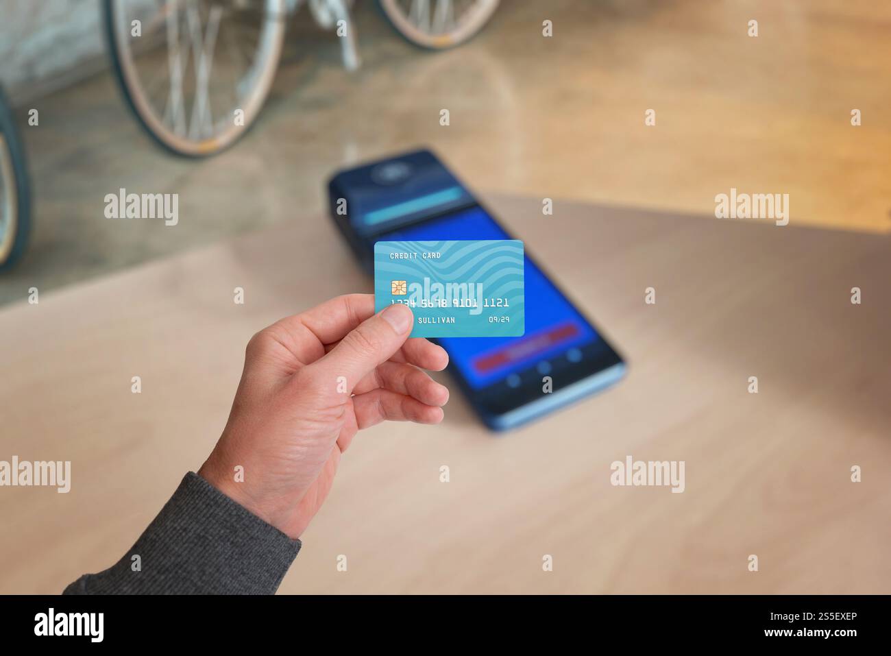 Eine Hand, die eine Kreditkarte über einem POS-Terminal hält, symbolisiert die kontaktlose Zahlung in Geschäften. Eine klassische Zahlungsmethode im modernen Handel Stockfoto
