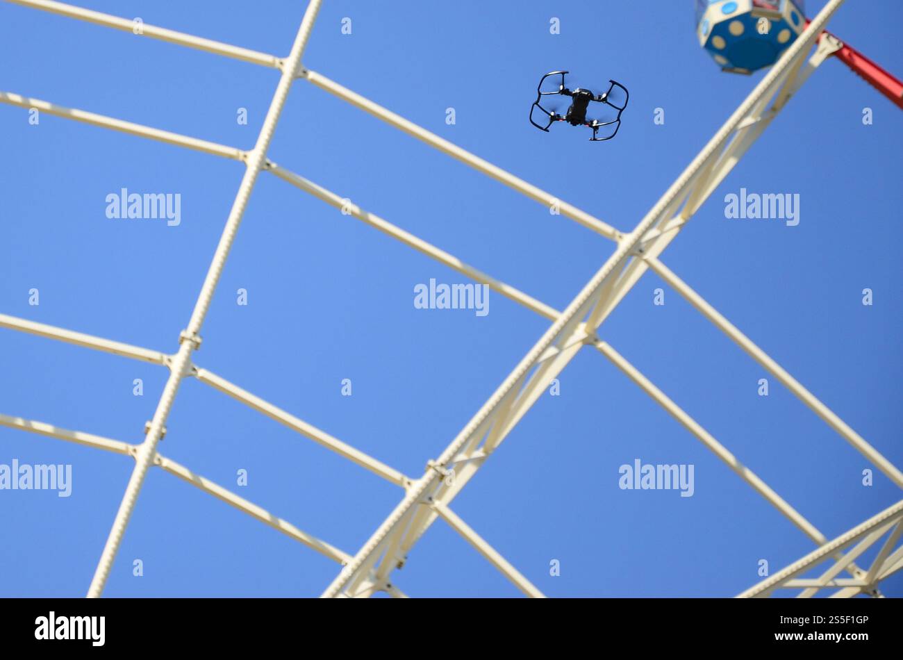 Drohne mit Fotokamera startet vom Land und fliegt für Fotos vor dem Riesenrad. Die Drohne startet vom Land und fliegt, um Fotos zu machen Stockfoto