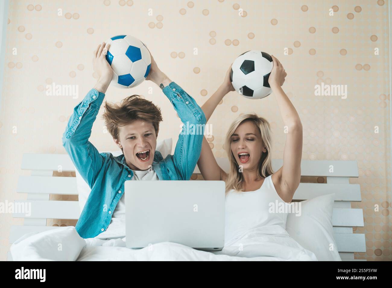 Glückliches Paar beim Fußballspielen auf dem Bett Stockfoto
