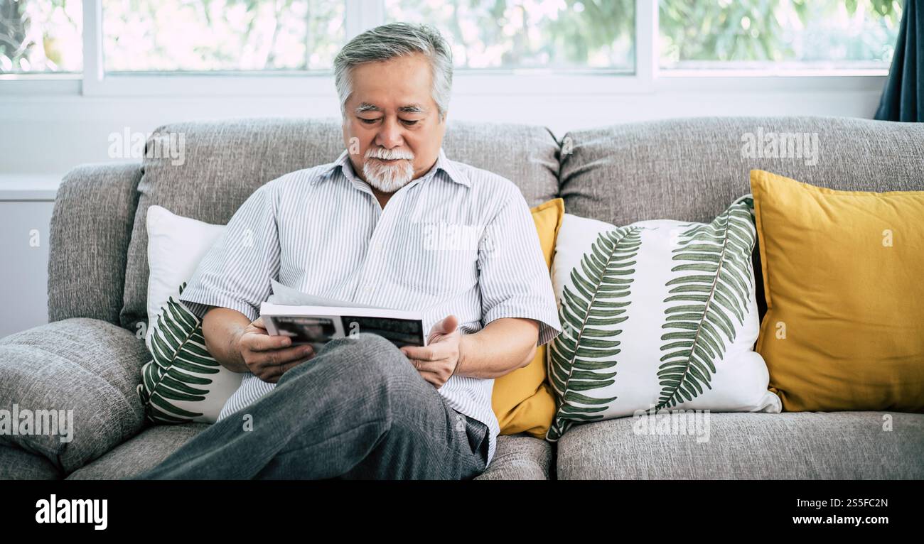 Ein alter Mann liest im Wohnzimmer Stockfoto