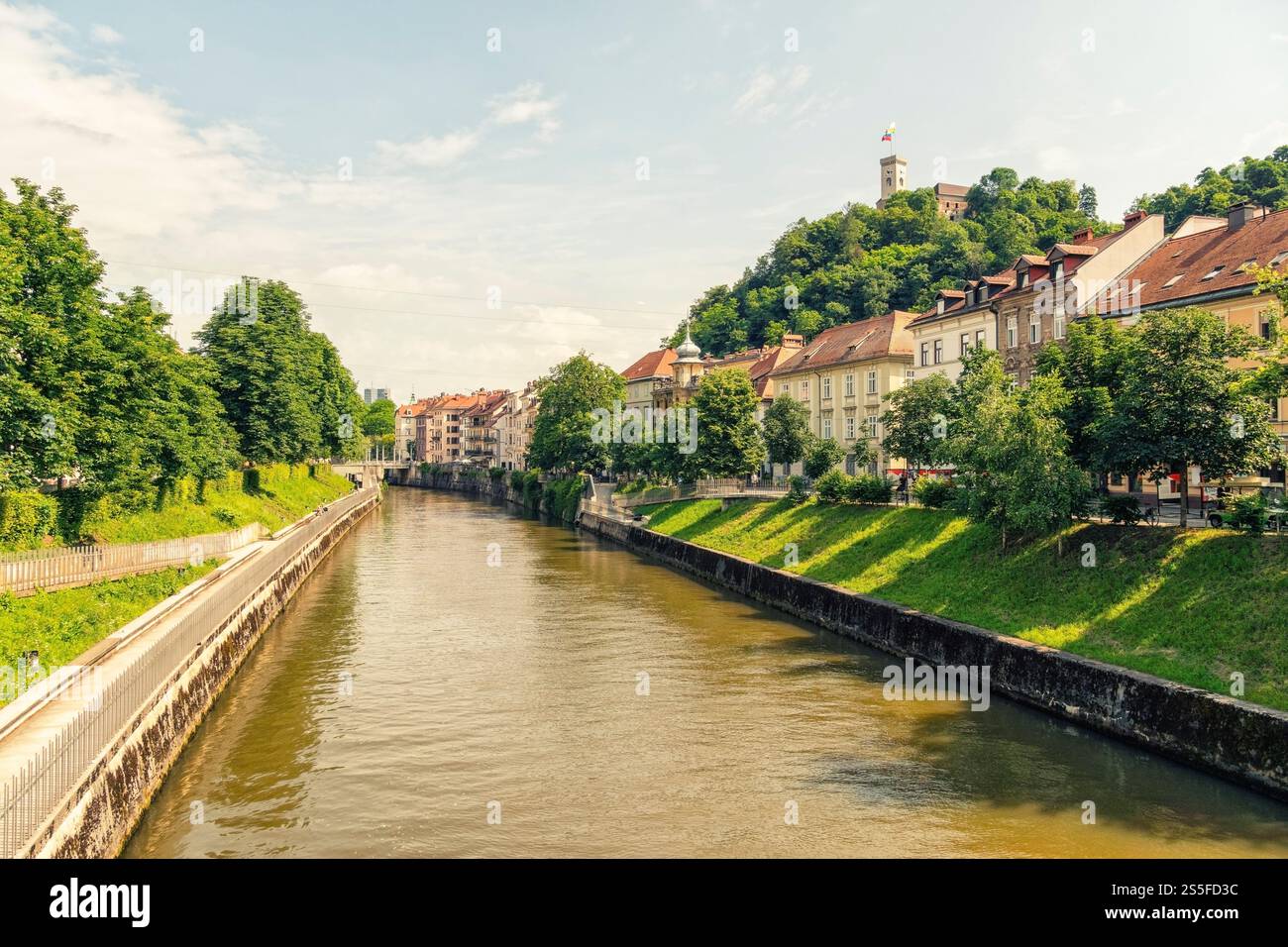 Sonniger Blick auf eine europäische Stadt mit historischen Gebäuden am Ufer des Flusses Ljubljana, mit Blick auf eine Burg auf einem Hügel, Ljubljana, Slowenien Stockfoto