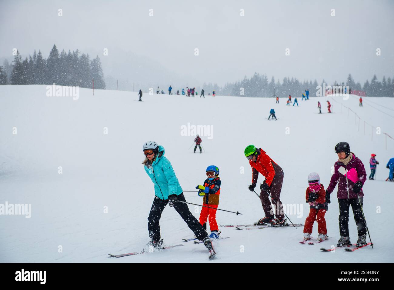 Familien genießen Skifahren auf den Pisten eines deutschen Skigebiets bei Schneefall. Stockfoto