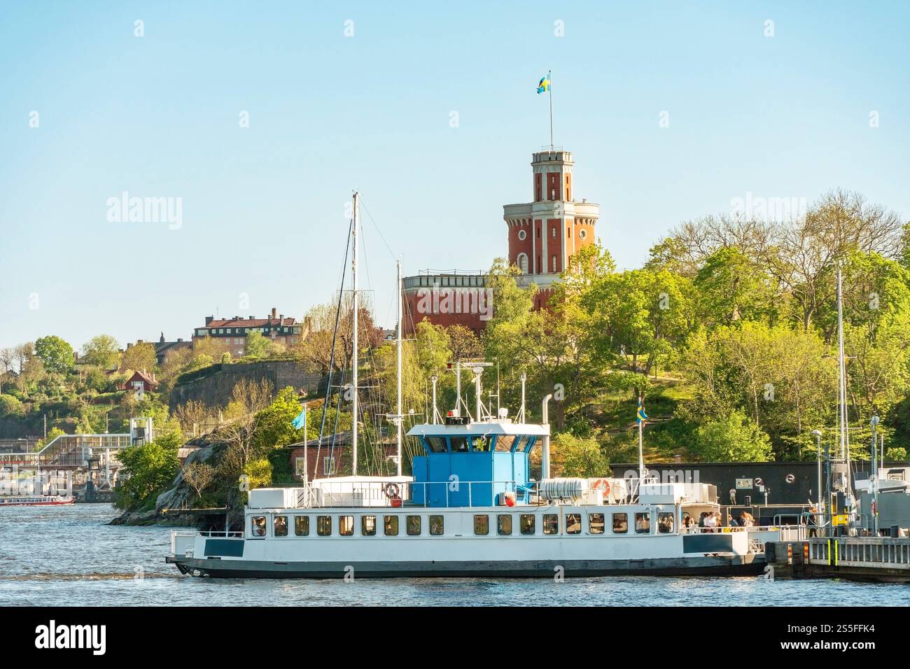 Passagierfähre namens Djurgarden 9 vor dem üppigen Grün und der historischen stockholmer Burg, Stockholm an einem klaren Tag, Schweden Stockfoto