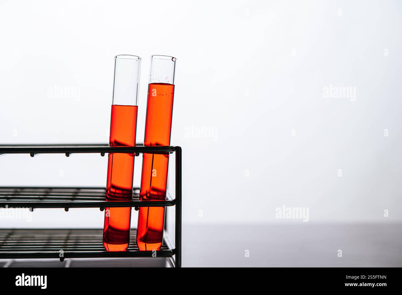 Orangene Chemikalien in einer wissenschaftlichen Glasröhre auf einem Regal. Stockfoto