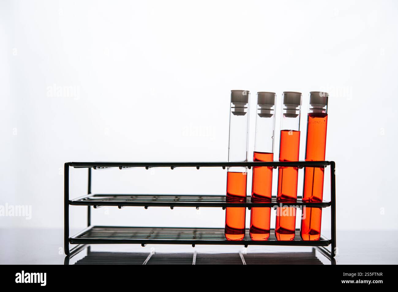 Orangene Chemikalien in einer wissenschaftlichen Glasröhre auf einem Regal. Stockfoto