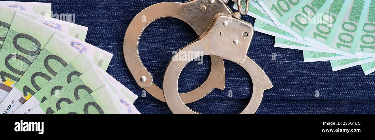 Der Fan von vielen Euro-Scheinen und Polizeihandschellen ist auf einer dunklen Jeansfläche. Hintergrundbild Stockfoto