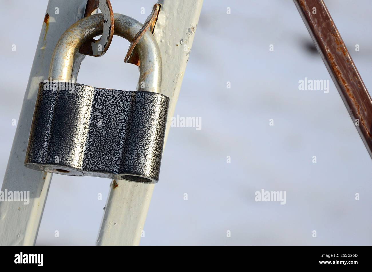 Ein großes graues Vorhängeschloss hängt an einem Metalltor Stockfoto