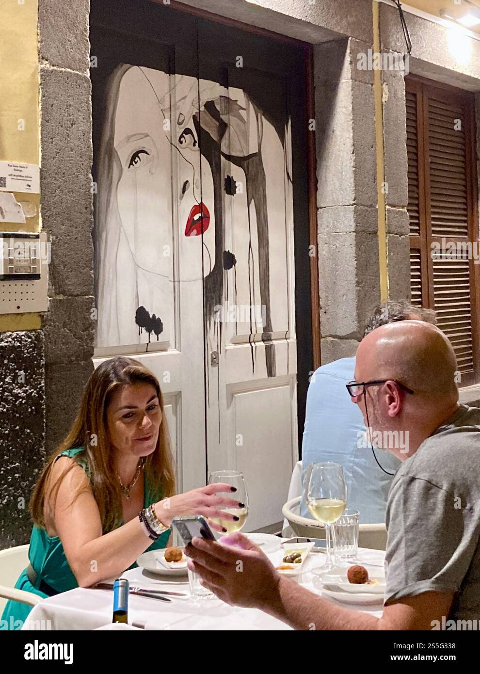 Ein Paar, das in der Rua de Santa Maria in der Zona Velha in Funchal, Madeira, zu Abend gegessen hat. - Smartphone-aufgenommenes Stockfoto