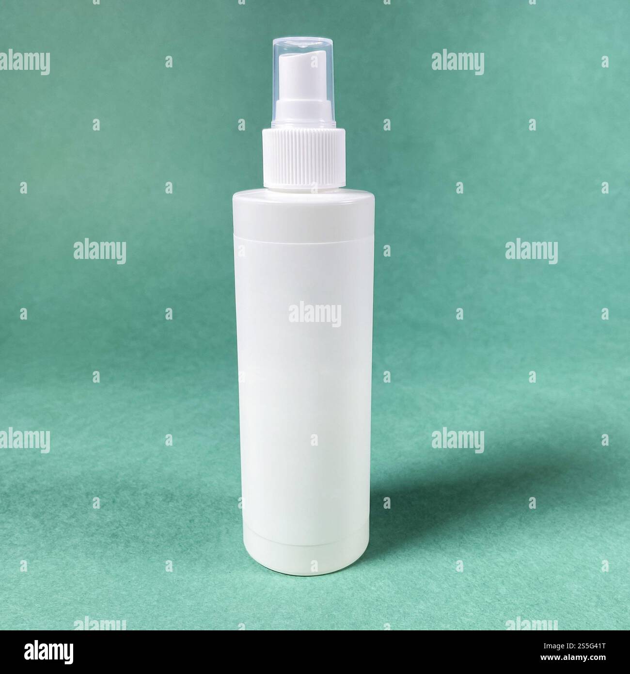 Weiße leere Sprühflasche aus Kunststoff auf grünem Papierhintergrund Stockfoto