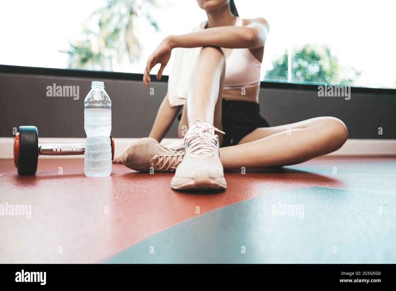 Frauen lehnen sich zurück und entspannen sich nach dem Training. Es gibt eine Wasserflasche und Kurzhanteln, selektiver Fokus Stockfoto