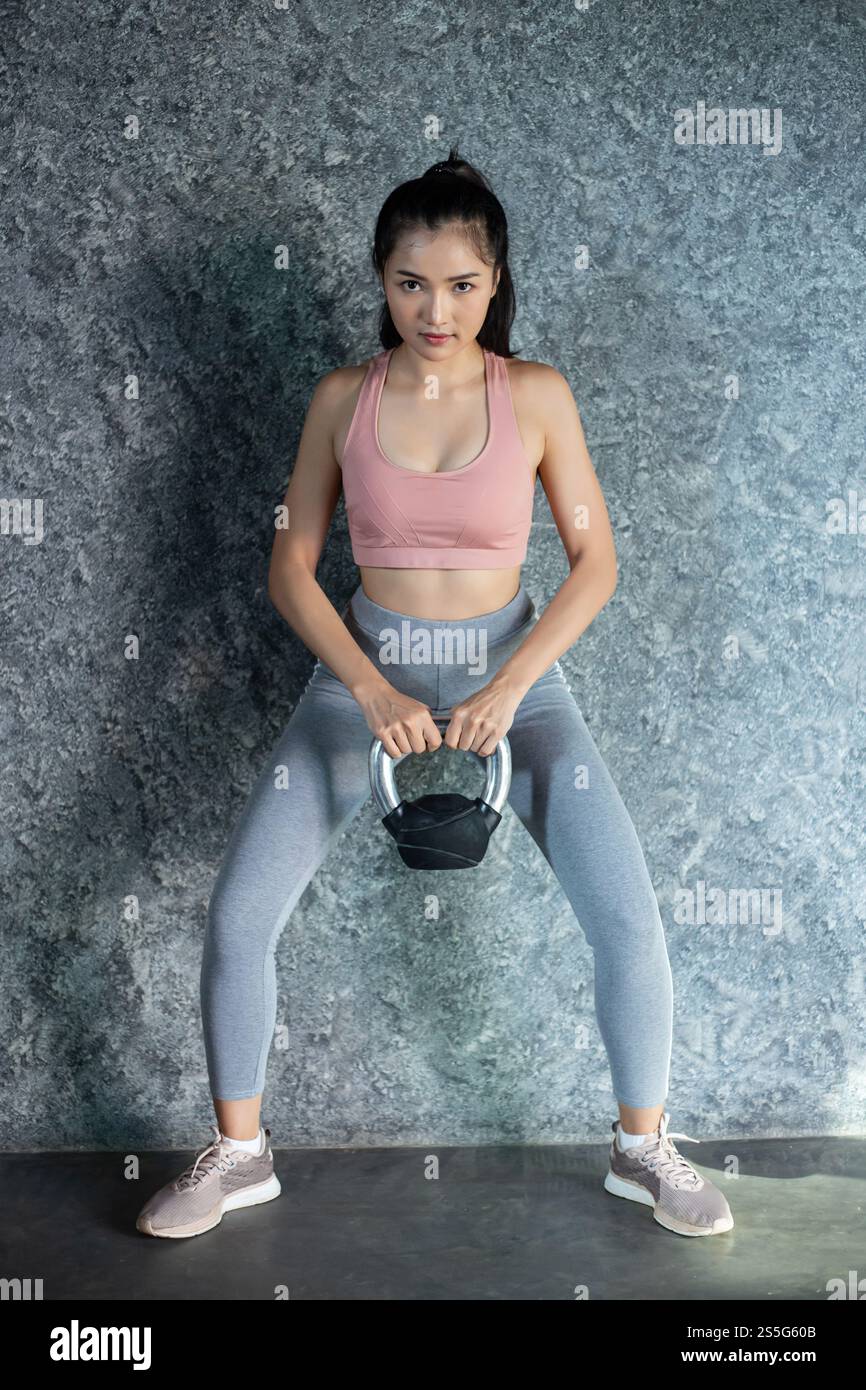 Asiatisches Mädchen, das mit der Kettlebell im Fitnessstudio trainiert. Stockfoto
