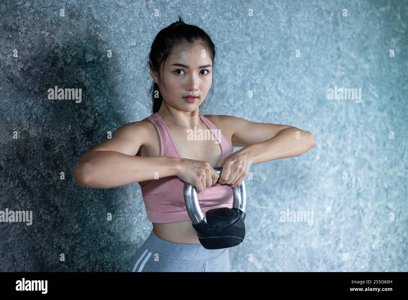 Asiatisches Mädchen, das mit der Kettlebell im Fitnessstudio trainiert. Stockfoto