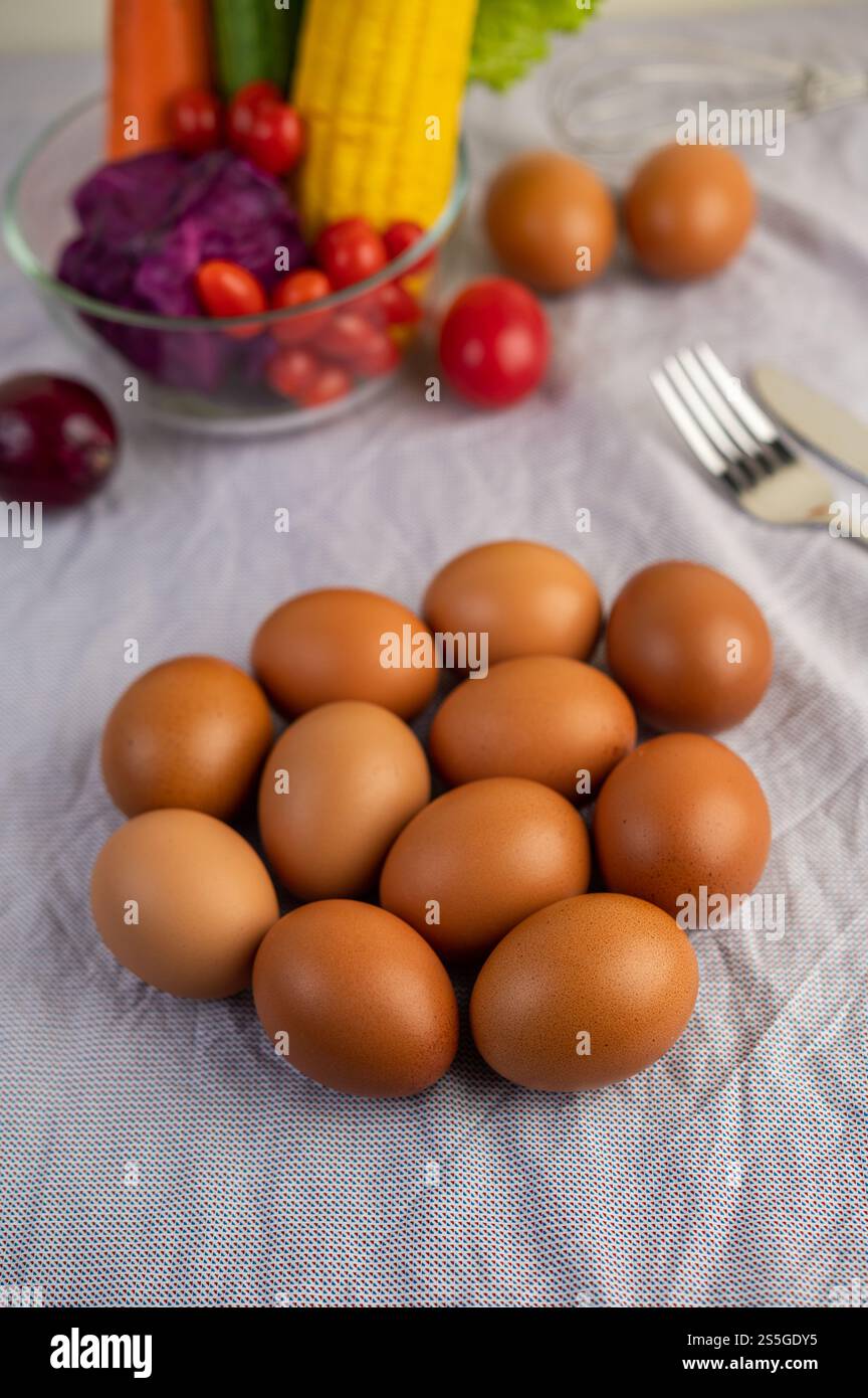Eier, die auf einem weißen Tuch liegen und Tomaten haben. Mais und Karotten Stockfoto