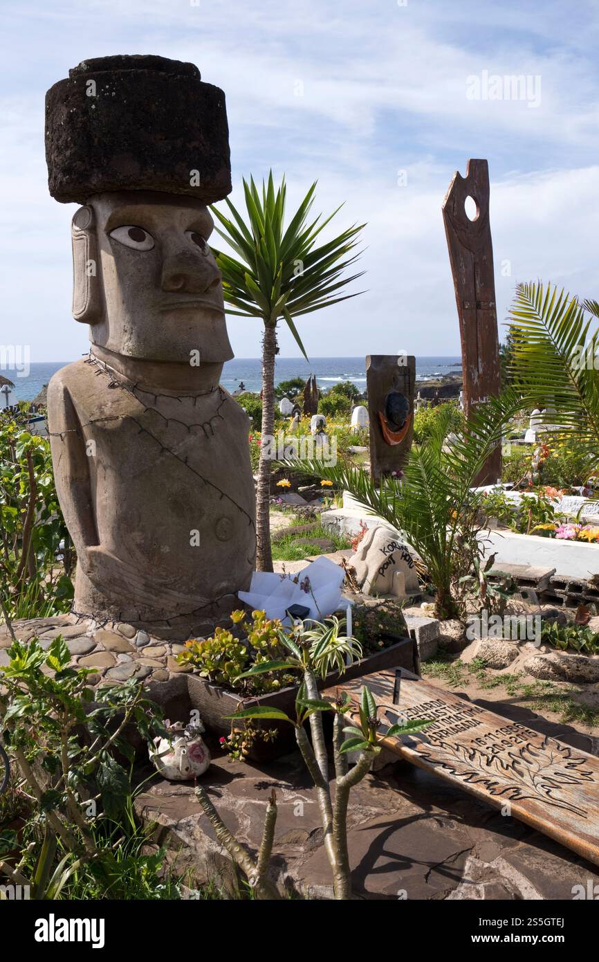 Ein Moai auf einem Grab auf dem Friedhof Hanga Roa zeigt christliche und einheimische Symbole, Osterinsel. Stockfoto