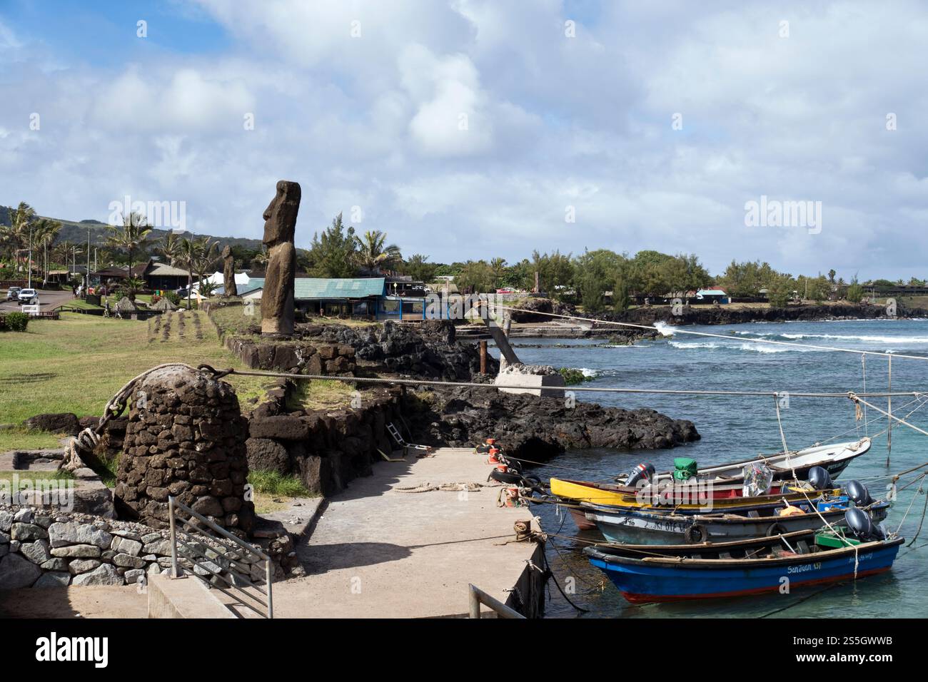 Fischerboote liegen neben Moai im kleinen Hafen in der Stadt Hanga Roa, Osterinsel. Stockfoto