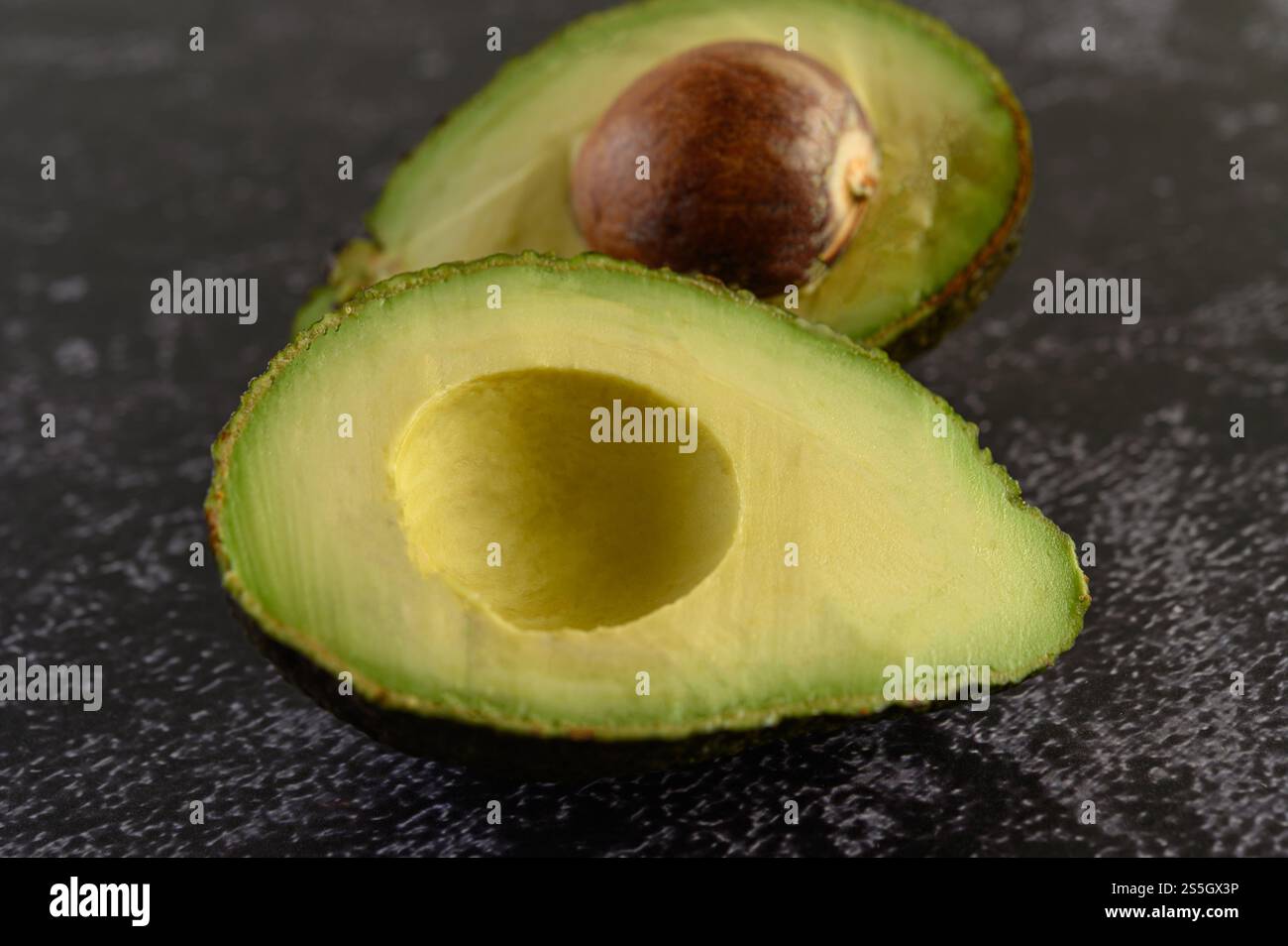 Halbe Avocado auf dem schwarzen Zementboden. Selektiver Fokus. Stockfoto