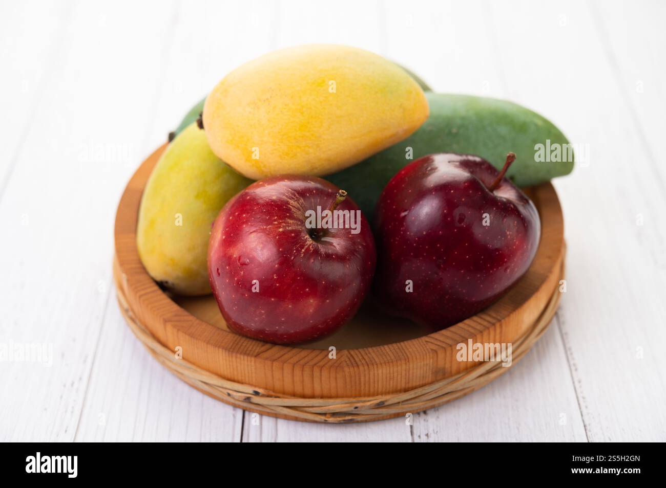 Äpfel und Mangos in einem Holztablett. Selektiver Fokus. Stockfoto
