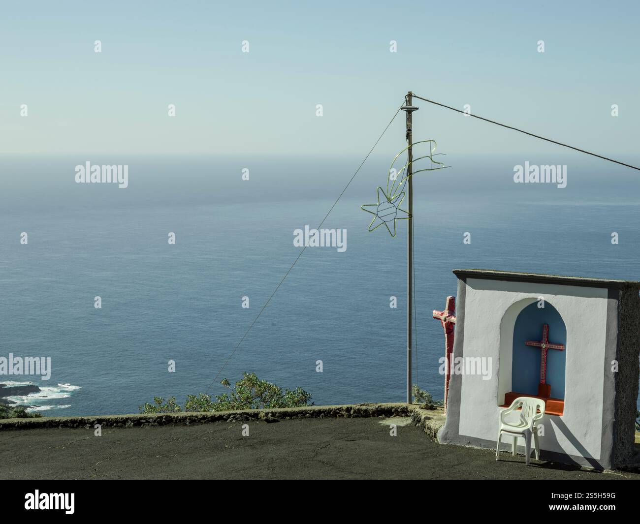 Eine heitere Weihnachtsszene an der Küste von La Palma mit einem glühenden Kreuz, festlichem Stern und Meerblick, die Natur, Glauben, und Urlaubscharme. Stockfoto