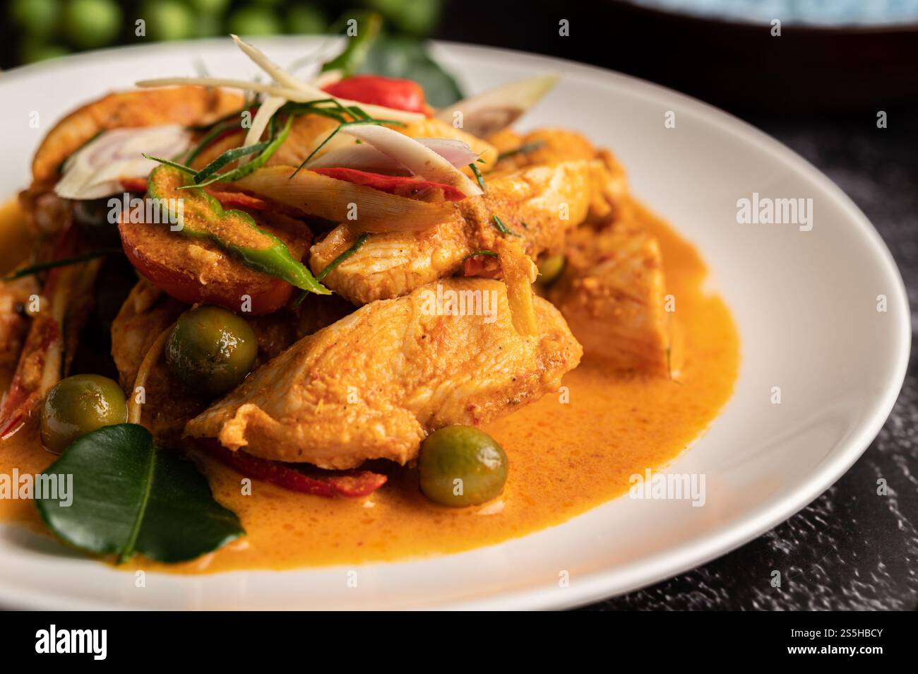 Trockenes grünes Curry mit Huhn in weißen Tellern auf schwarzem Zement Stockfoto