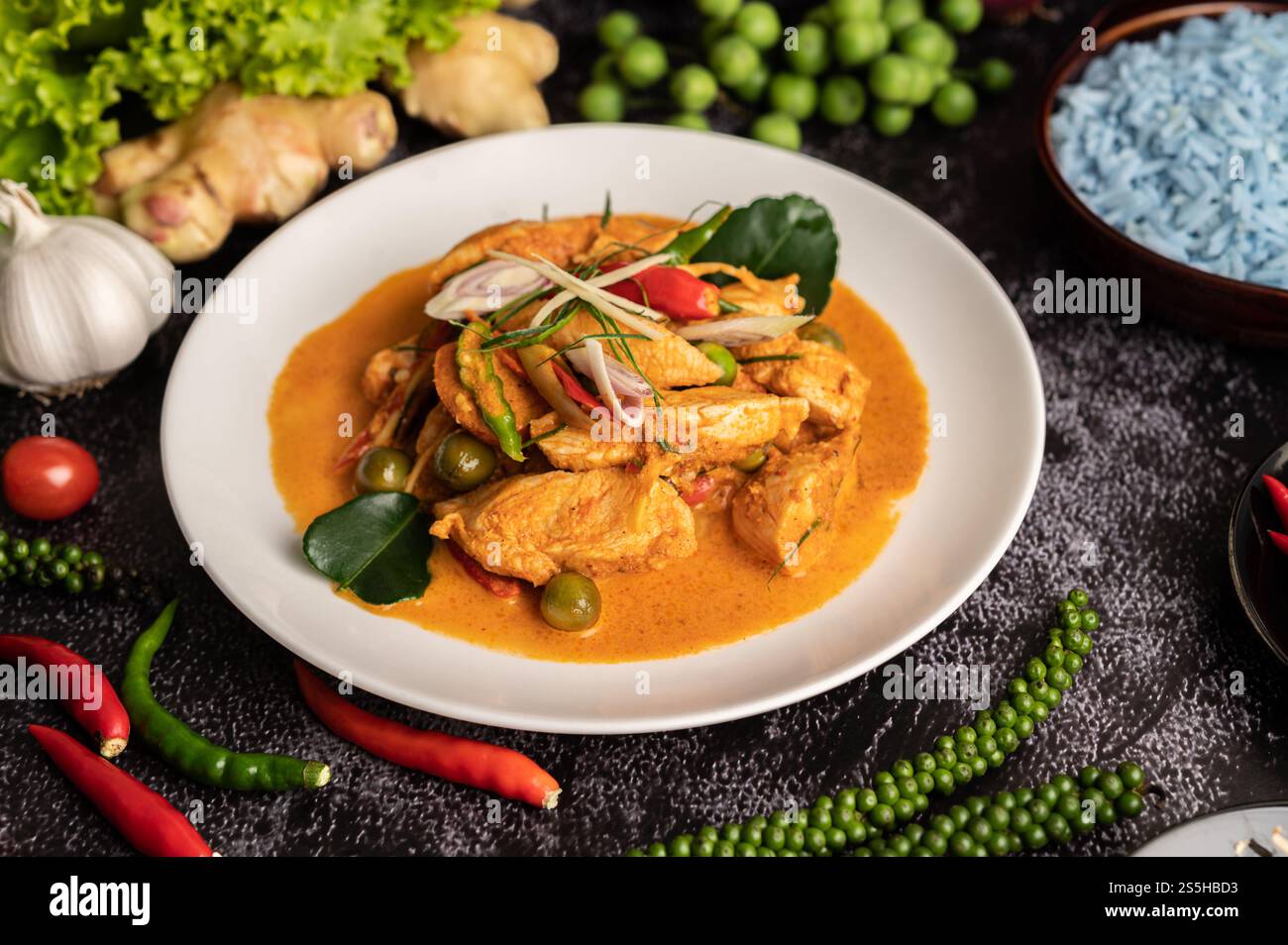 Trockenes grünes Curry mit Huhn in weißen Tellern auf schwarzem Zement Stockfoto