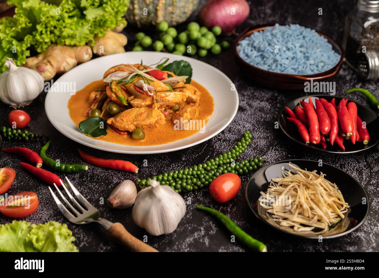 Trockenes grünes Curry mit Huhn in weißen Tellern auf schwarzem Zement Stockfoto