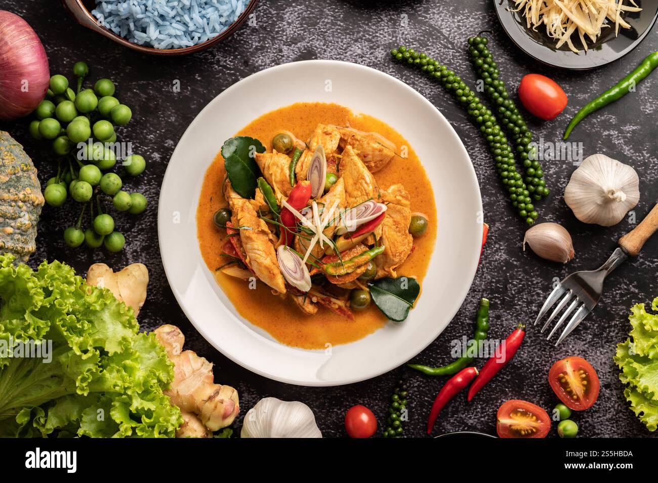 Trockenes grünes Curry mit Huhn in weißen Tellern auf schwarzem Zement Stockfoto