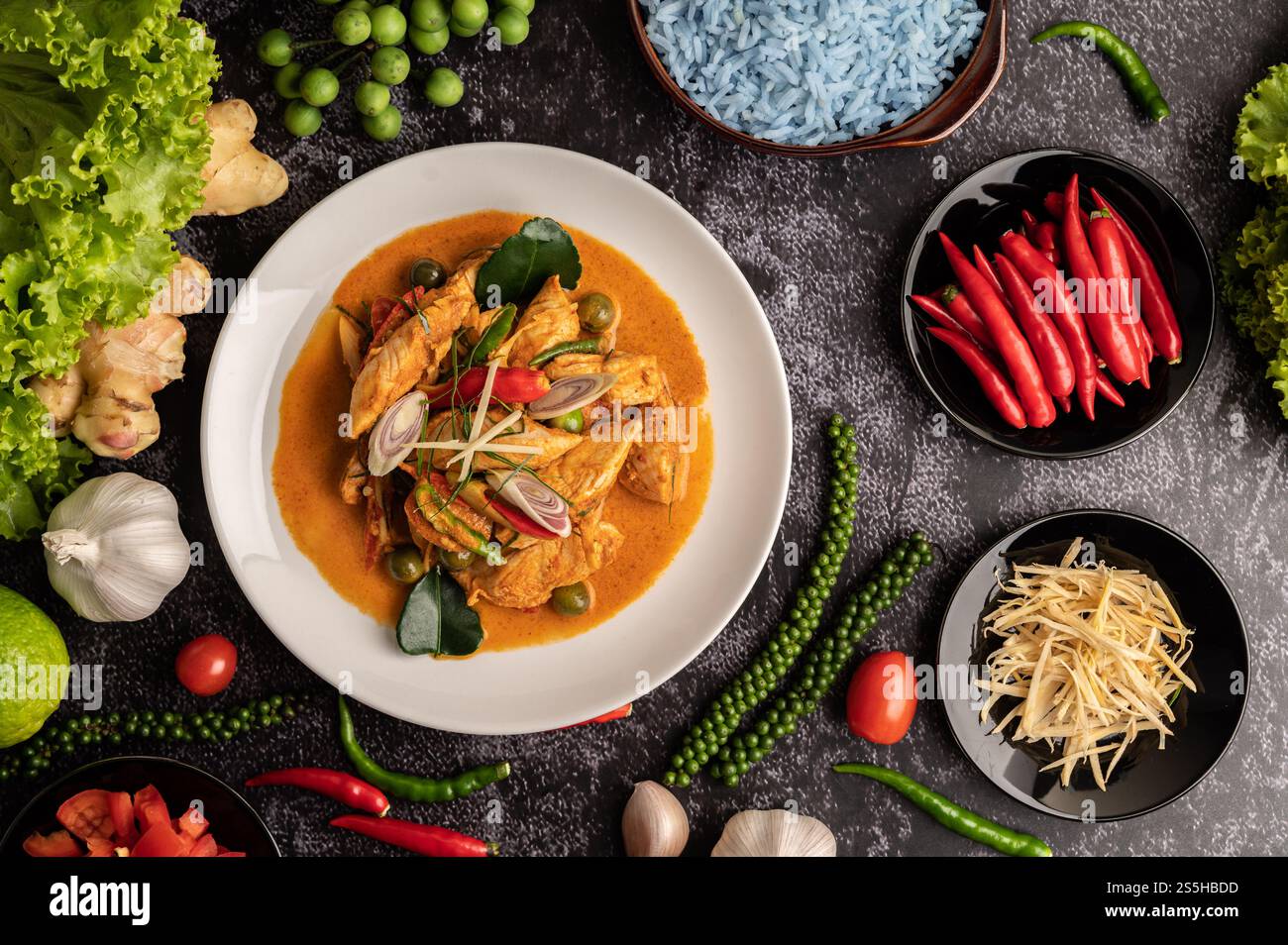 Trockenes grünes Curry mit Huhn in weißen Tellern auf schwarzem Zement Stockfoto