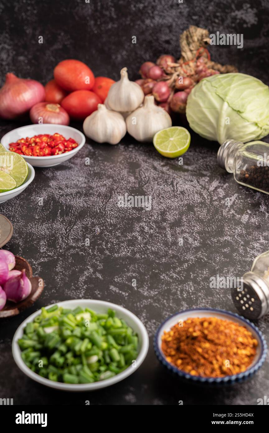 Gehackte Zwiebeln und Cayennepfeffer in einer Tasse auf schwarzem Zement. Stockfoto