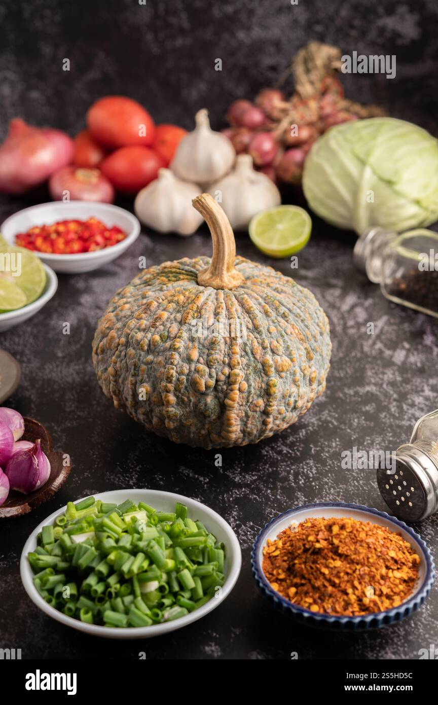 Gehackte Schalotten, Kürbis und Cayennepfeffer in einer Tasse auf schwarzem Zement. Stockfoto