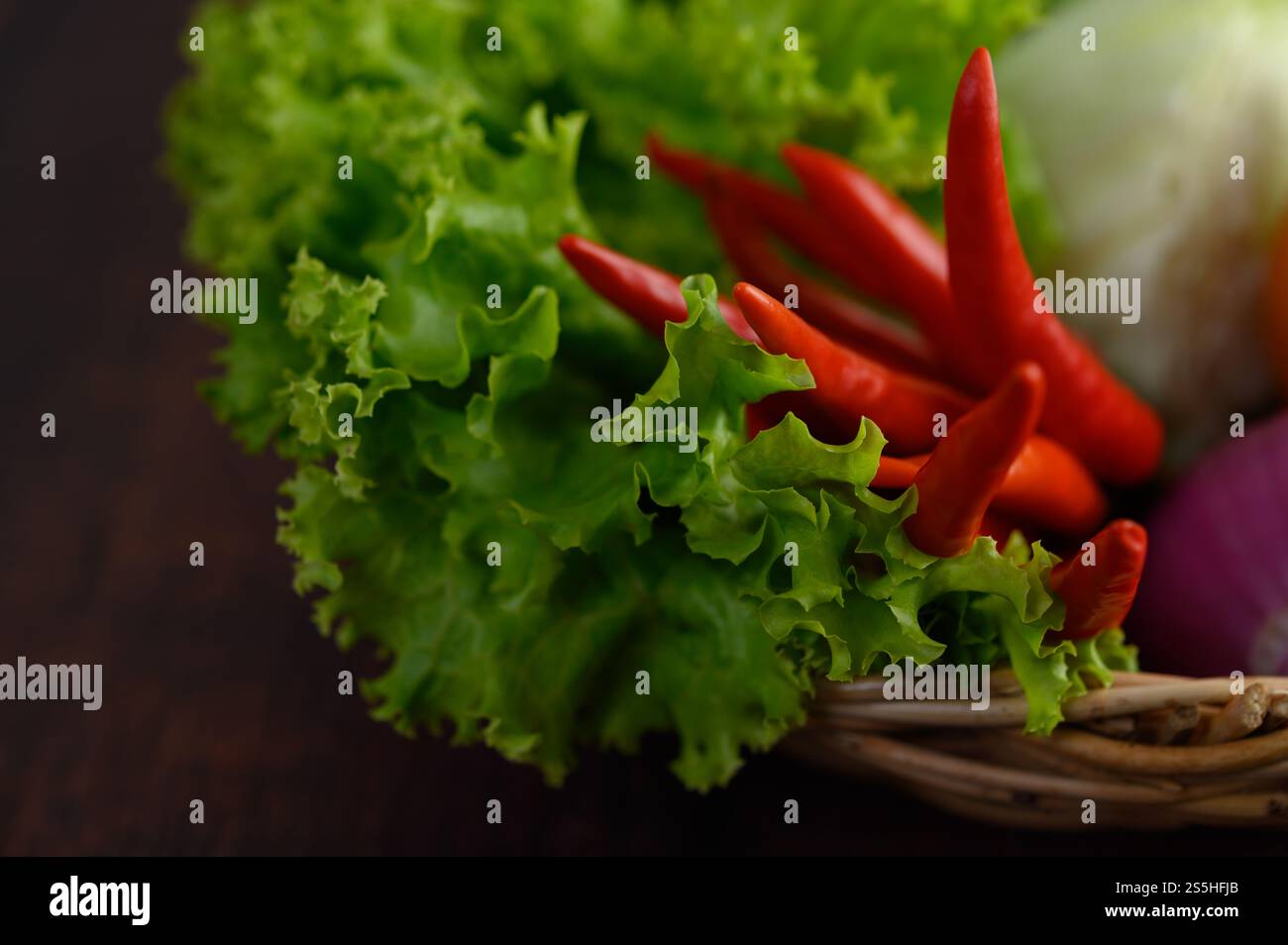 Selektiver Fokus mit grünem Salatblatt, rotem Chili im Webkorb und leerem Platz zum Einfügen von Text Stockfoto